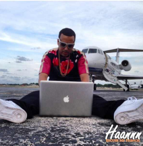 French Montana sitting in front of Private Jet, while using MacBook Pro